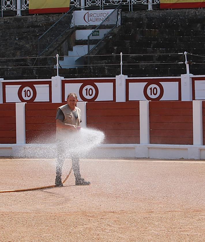 Imagen secundaria 2 - A la izquierda, Alfredo López se encarga cada año de que todo quede preparado para las faenas; a la derecha, Fernando Morata riega la arena para que quede asentada.