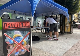 Cartel de rechazo de la Pitufa Karateca, junto a la mesa de recogida de firmas de La Pola.