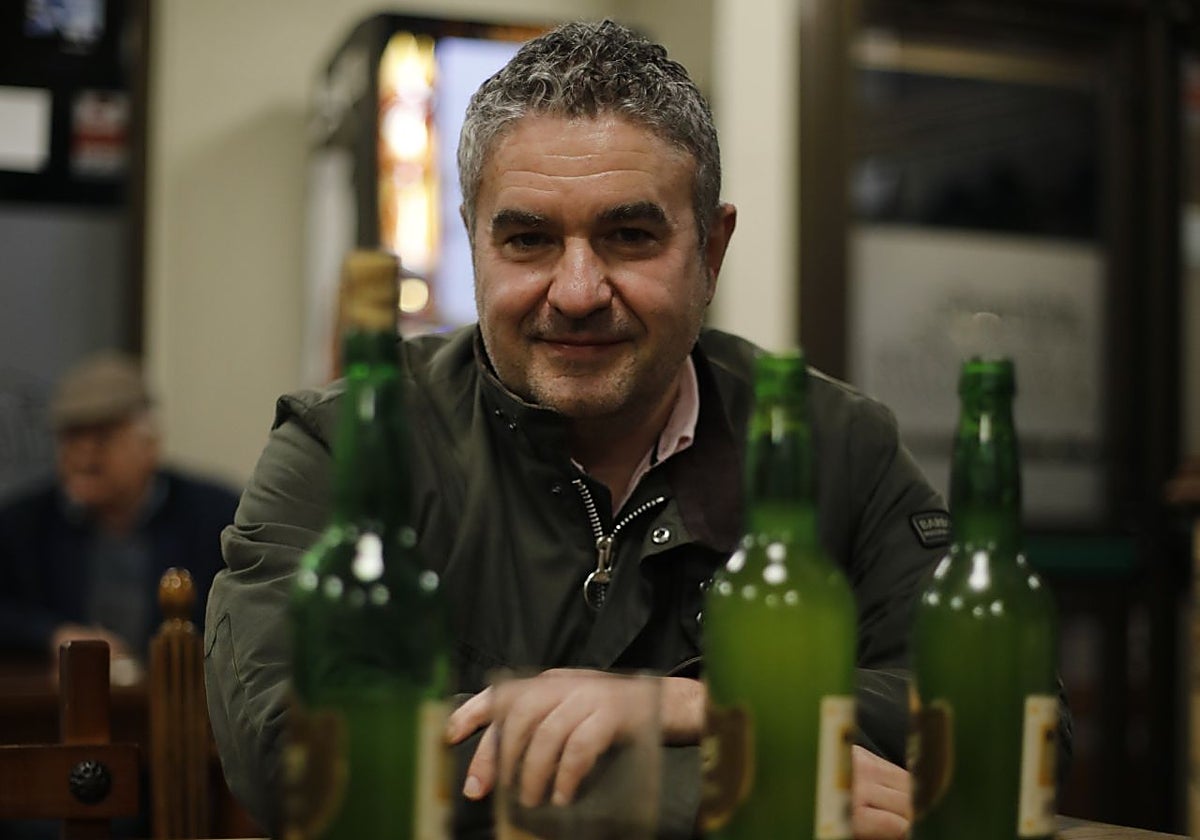 Luis Benito García posa tras varias botellas y un vaso, la forma de consumir la sidra desde finales del XIX.