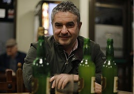 Luis Benito García posa tras varias botellas y un vaso, la forma de consumir la sidra desde finales del XIX.