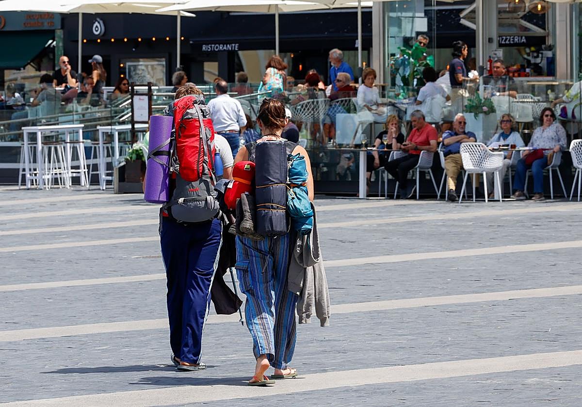 Una pareja de turistas camina por los Jardines de la Reina de Gijón.