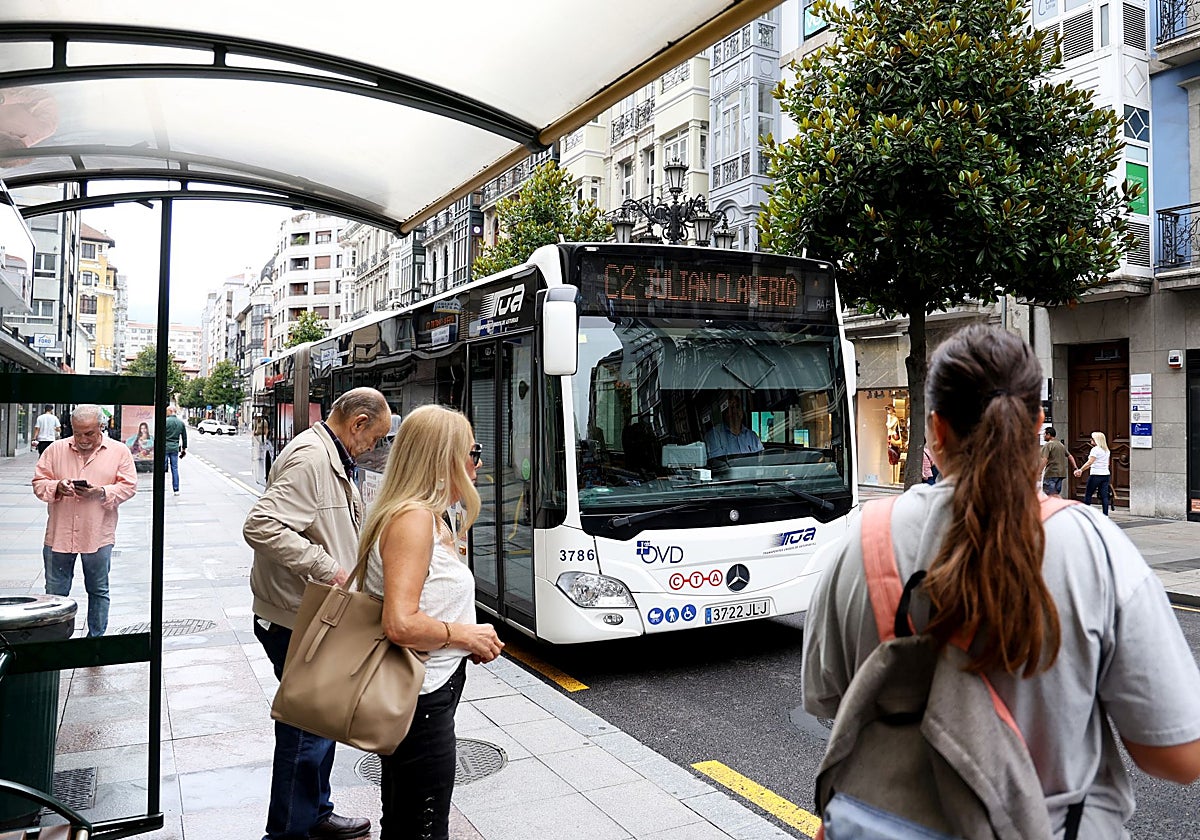 Usuarios en la parada de autobús de la calle Uría.
