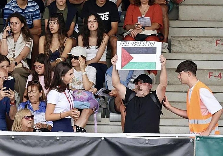 Un hombre muestra la bandera de Palestina durante la participación de un jinete israelí en el Hípico de Gijón.