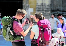 Dos peregrinos, con las mochilas a sus espaldas, sacan una foto a la credencial que acredita su paso por la Catedral de San Salvador.