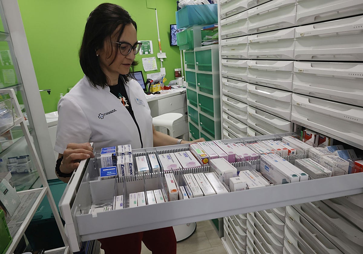 Una profesional busca un medicamento en una farmacia.