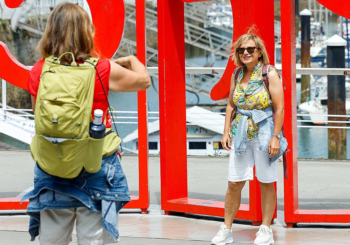 Una turista inmortaliza a su amiga ante las Letronas de Gijón.