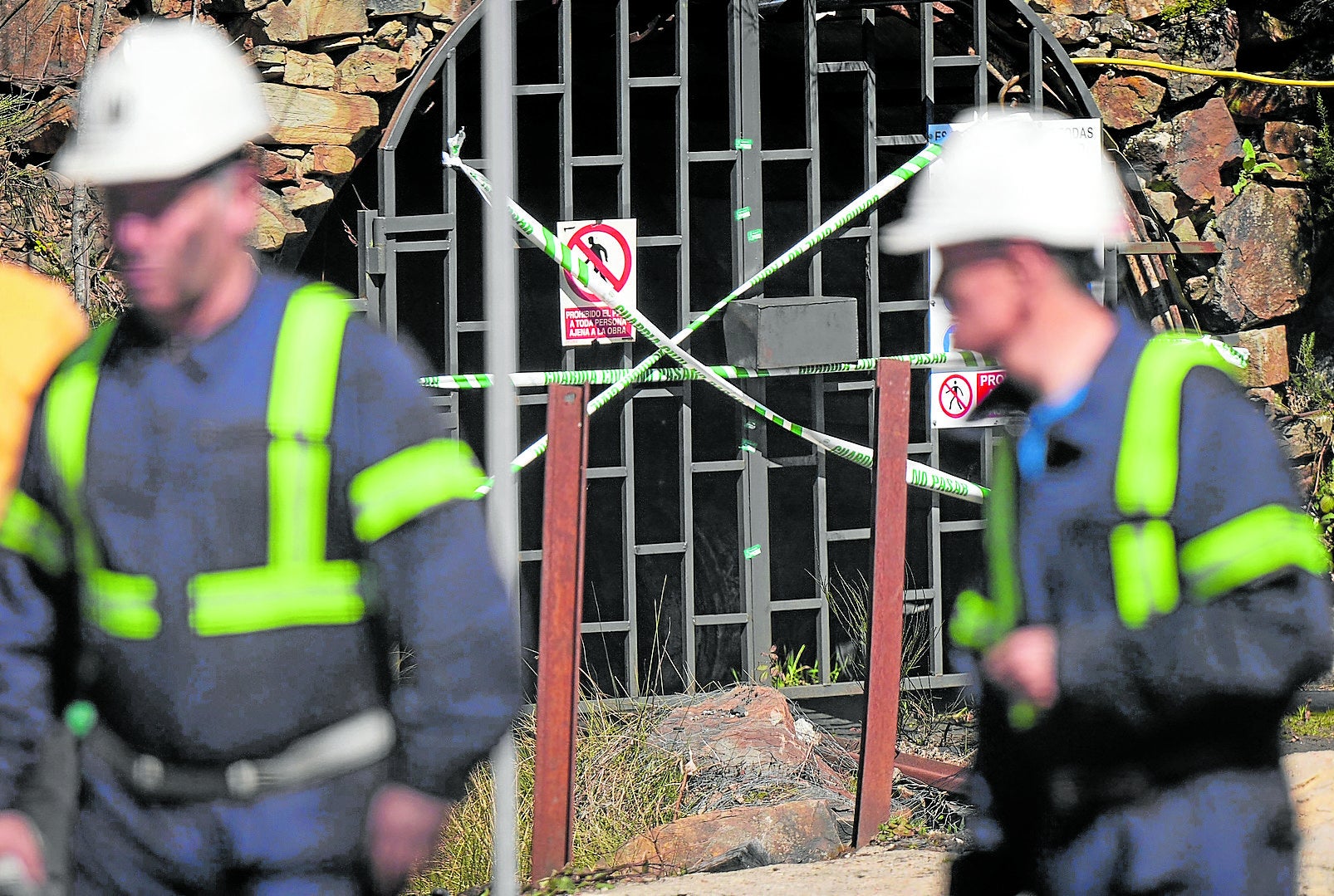 Dos mineros pasan ante la boca de la mina de Cerredo, clausurada tras el accidente que costó la vida a cinco mineros.