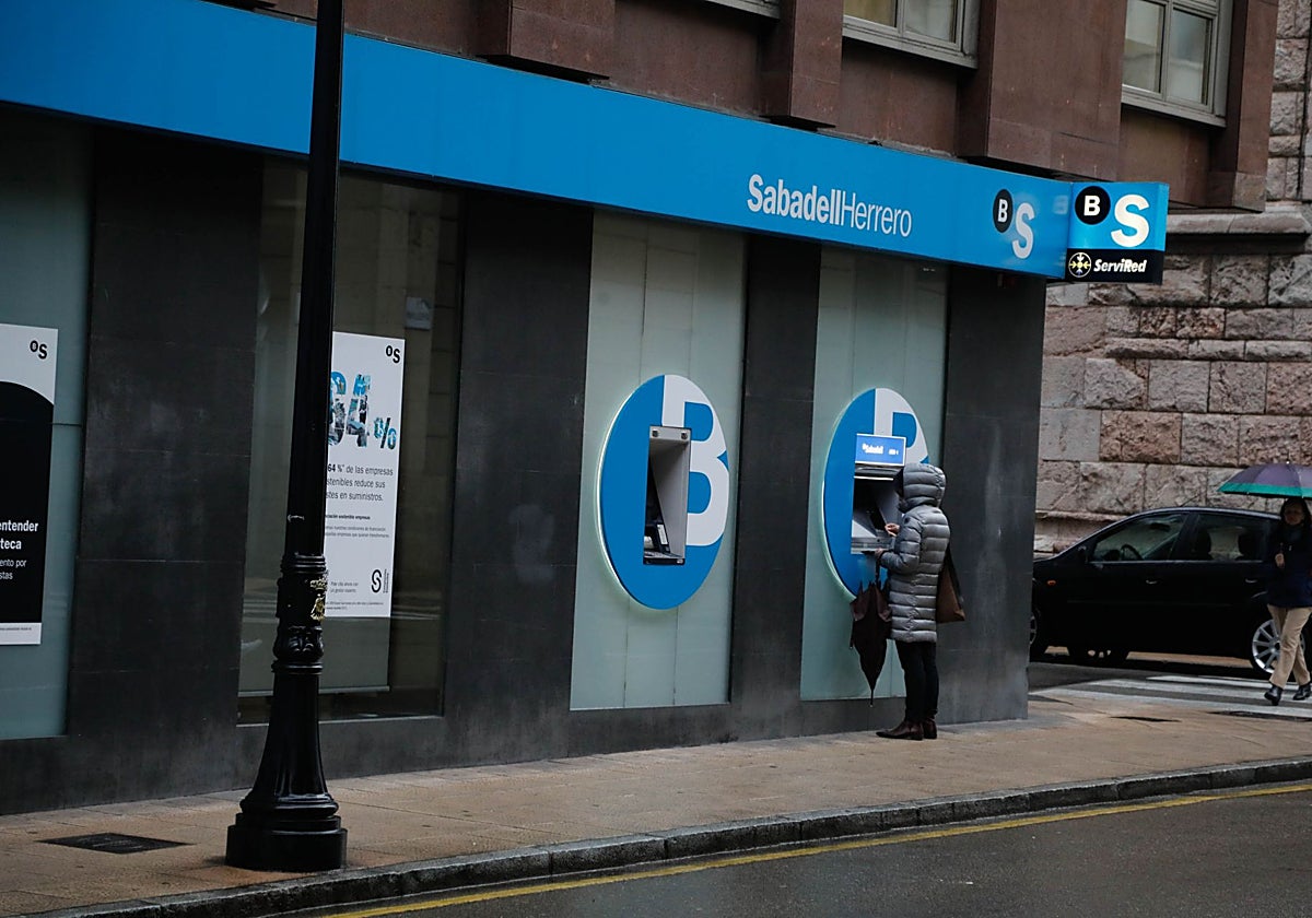 Una ciudadana opera en un cajero de Sabadell Herrero, la marca asturiana del banco catalán.
