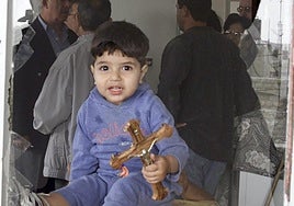 Un niño cerca de Belén, con una cruz, entre escombros y restos de artillería.