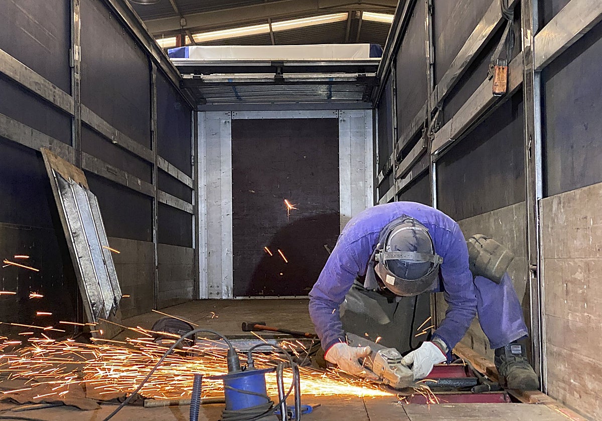 Un trabajador realiza tareas de reparación en la plataforma de un camión, en una empresa de Gijón.
