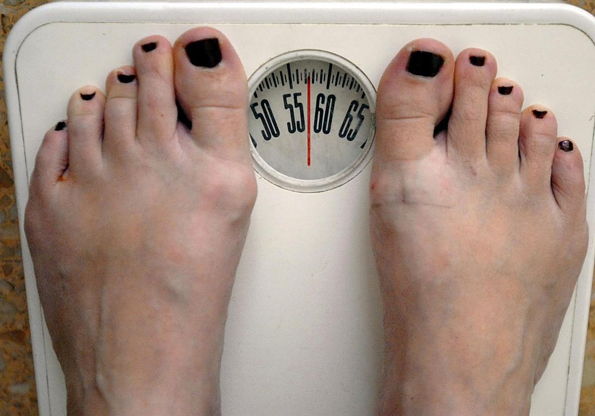 Una persona se pesa en una báscula.