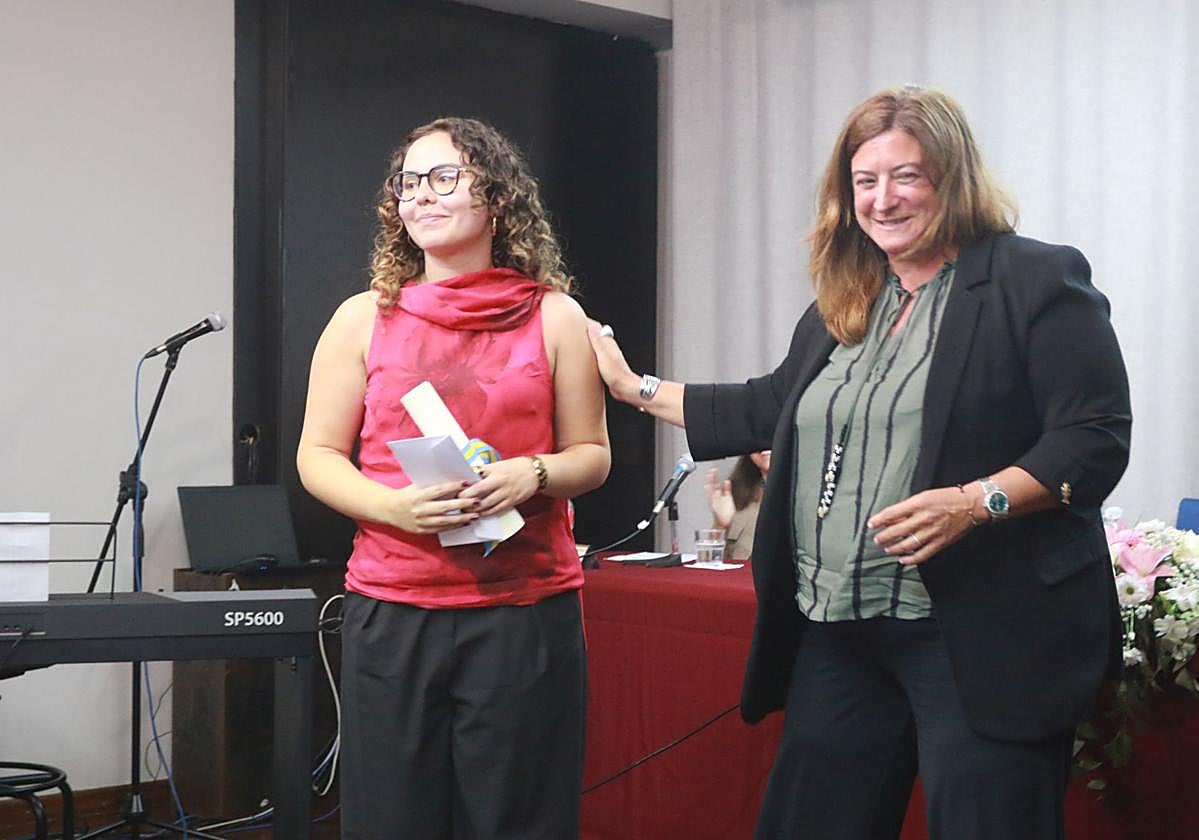 Irene García-Pumarino Arias recibe el diploma del premio Aurelio Menéndez-Mercedes García Quintana de manos de la directora del IES Jovellanos, Idoya Martínez, en el salón de actos del centro.