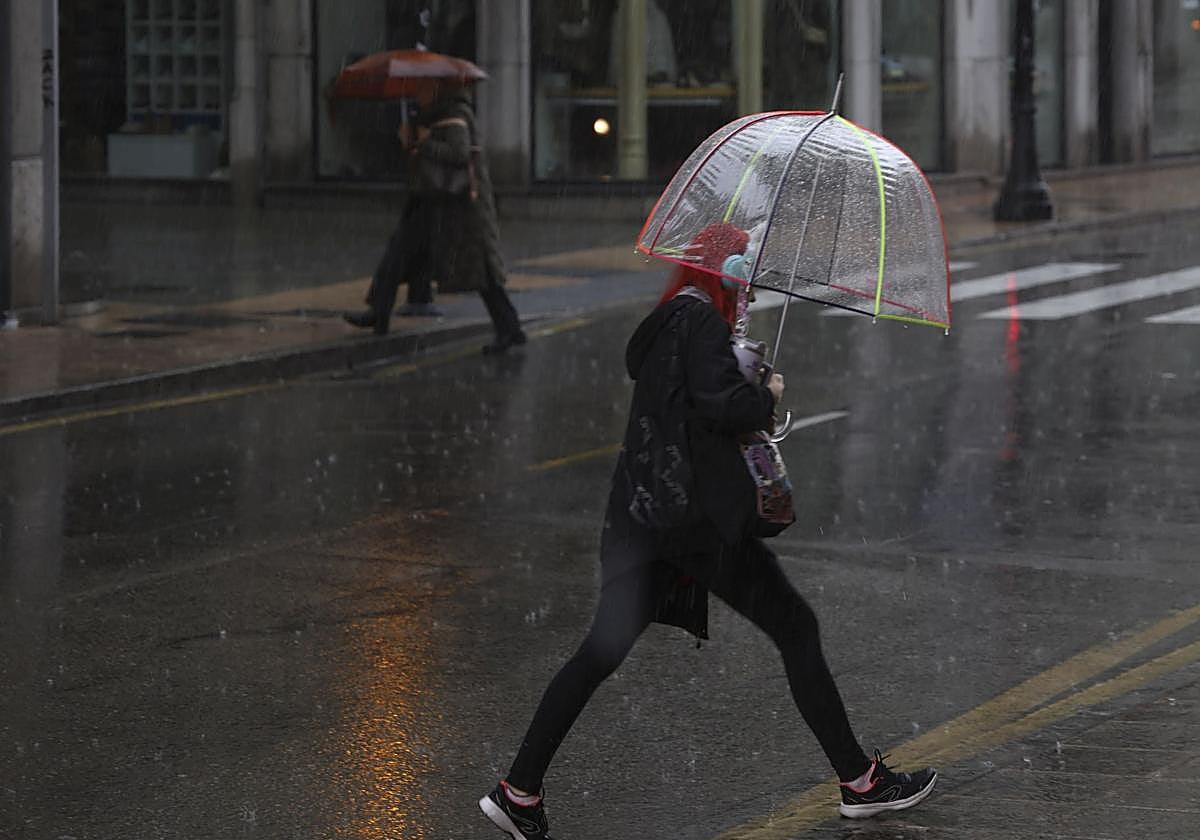 Una mujer camina bajo la lluvia de este lunes en Gijón.