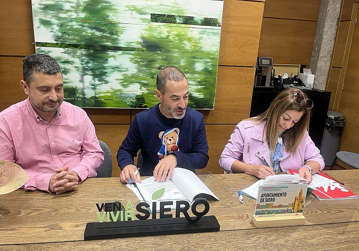 El alcalde de Siero, el socialista Ángel García, 'Cepi', firma el acuerdo presupuestario con la portavoz de IU, Tere Álvarez, ante la mirada del edil Javier Rodríguez (a la izquierda de la imagen).