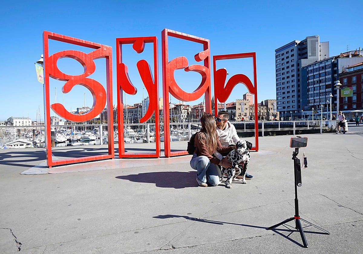 Una pareja se fotografía ante las Letronas de Gijón.