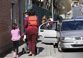 Una mujer, que empuja una silla infantil, camina con sus hijos tras la salida del colegio.