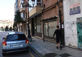 Un joven pasea a su perro por delante de varios bajos comerciales cerrados.