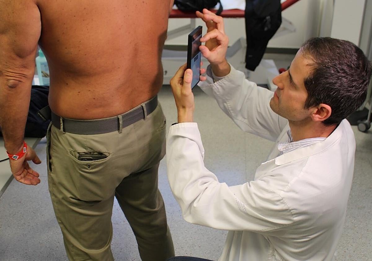 Un doctor toma una fotografía de una lesión dermatológica de un paciente para cargarla al programa de inteligencia artificial que elaborará un informe.