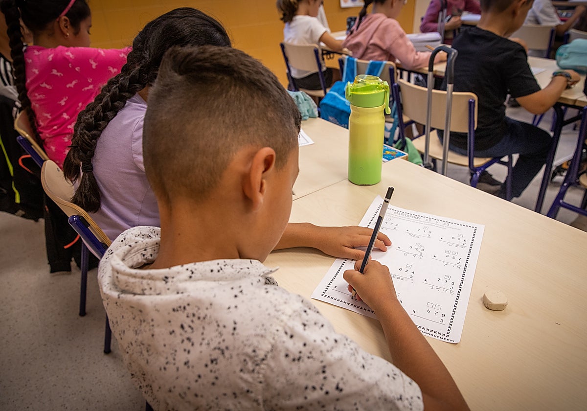 Un niño hace operaciones matemáticas en el colegio.