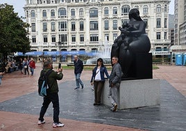 Unos turistas se fotografían con la escultura de Botero en la plaza de La Escandalera.