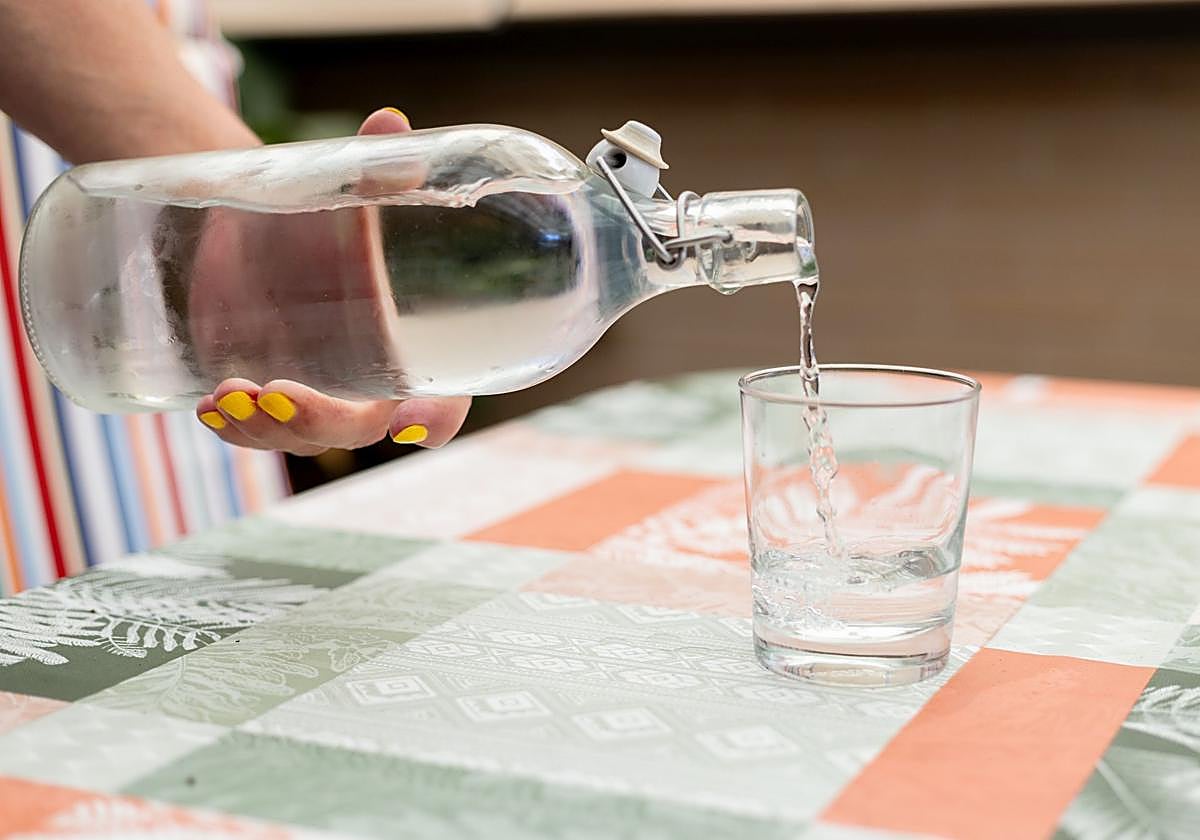 Una persona sirve un vaso de agua.