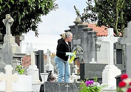 Una mujer limpia una de las lápidas del cementerio de El Salvador.