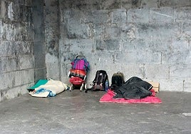 Una persona sin hogar duerme en la calle junto a sus pertenencias.