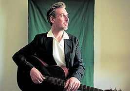 El músicu corverán posa cola so guitarra.