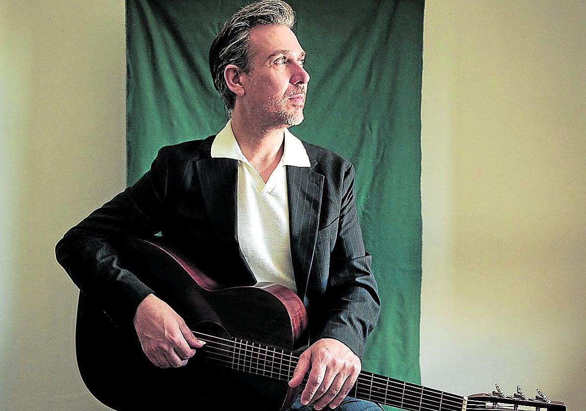 El músicu corverán posa cola so guitarra.