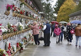 Una familia coloca flores en un nicho del cementerio de Deva, en Gijón.