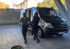 Uno de los detenidos es trasladado a un furgón en el cuartel de Sama de Langreo para llevarlo al juzgado de Pola de Siero.