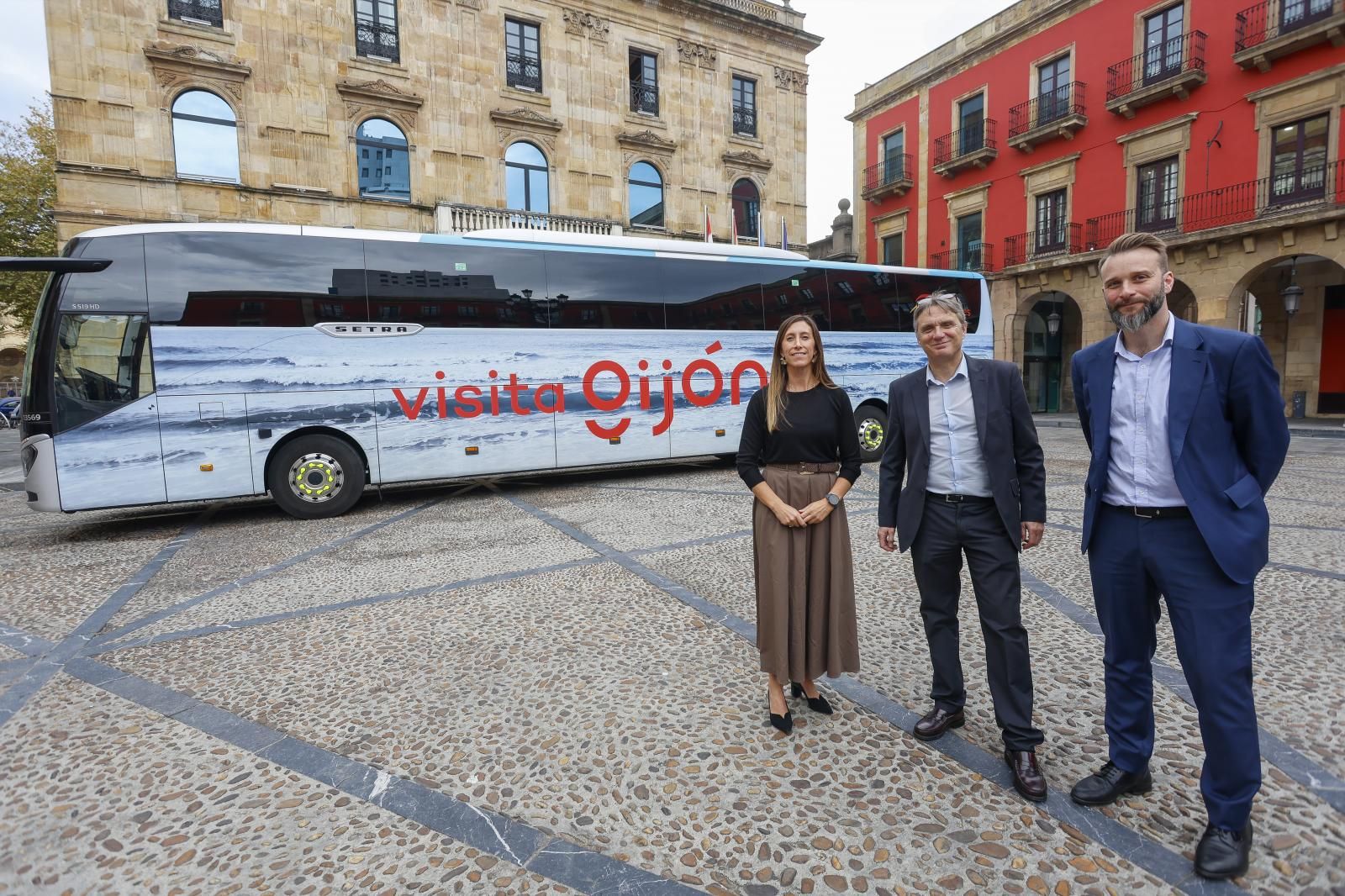 Ángela Pumariega, Quintin Fernández y Daniel Martínez Junquera posan junto a uno de los autobuses de la campaña de promoción.