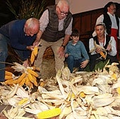 Un grupo de personas de todas las edades esfoyan las panoyas en el Pueblu d'Asturies
