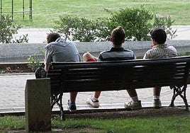 Varios jóvenes sentados en el banco de un parque.