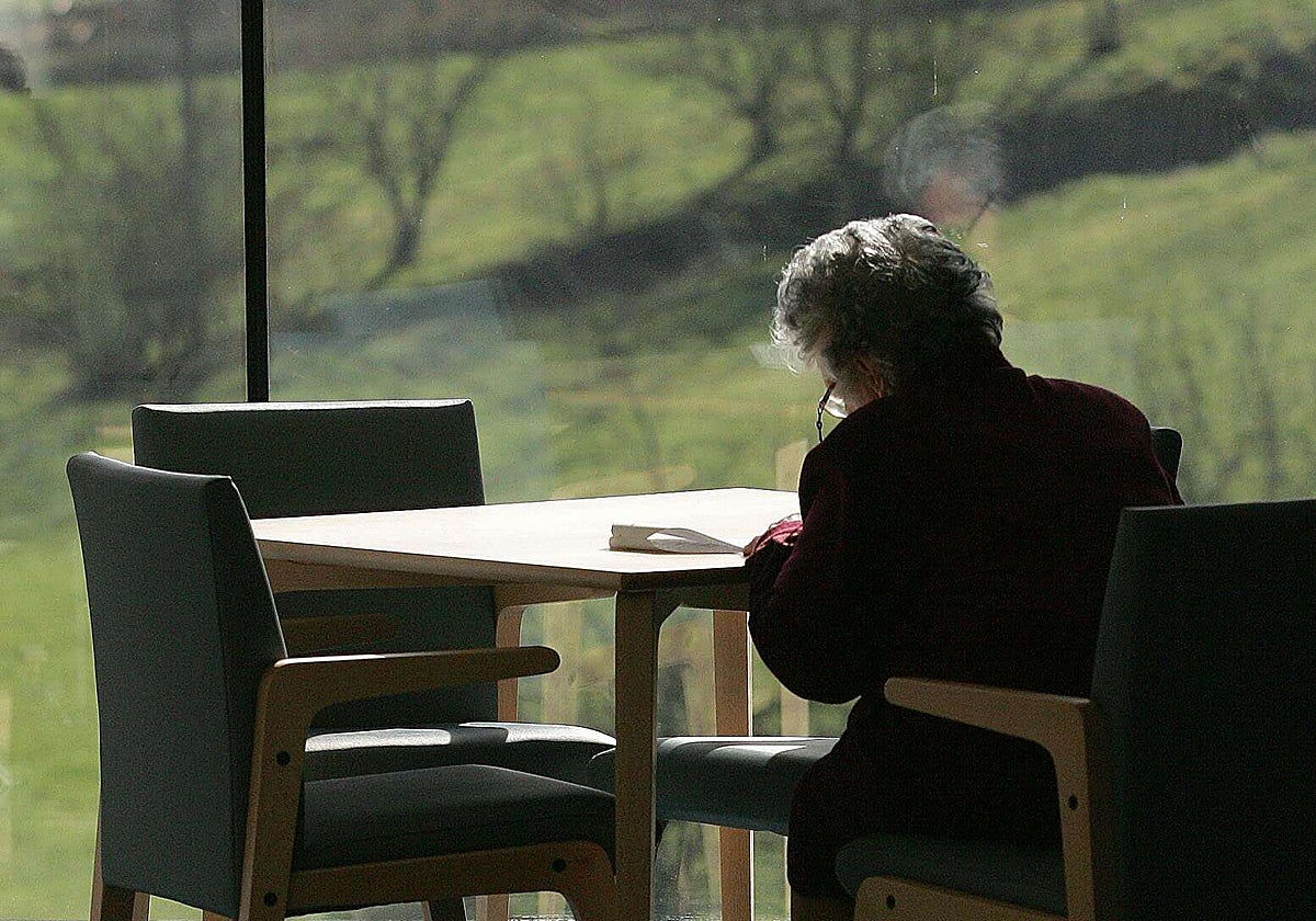 Una mujer lee en soledad en un centro sociosanitario.