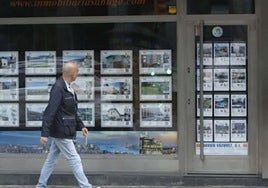 Un ciudadano se fija en las ofertas de una inmobiliaria de Gijón.