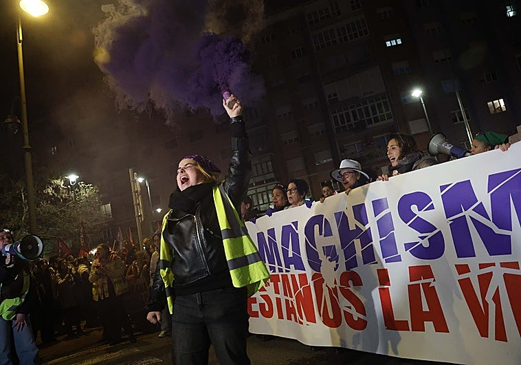Una de las integrantes de la Plataforma Asturias Feminista, con una bengala malva, ante la pancarta de cabecera.