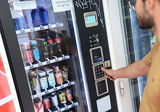 Un joven adquiere bebidas energéticas en una máquina expendedora.