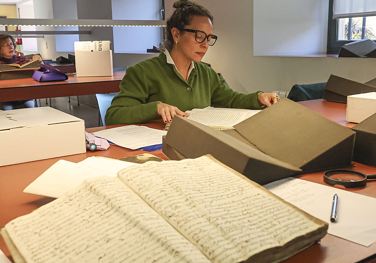 Dos de las voluntarias del Archivo Histórico Diocesano bucean en los libros parroquiales en busca de partidas que acrediten el origen de los emigrantes.