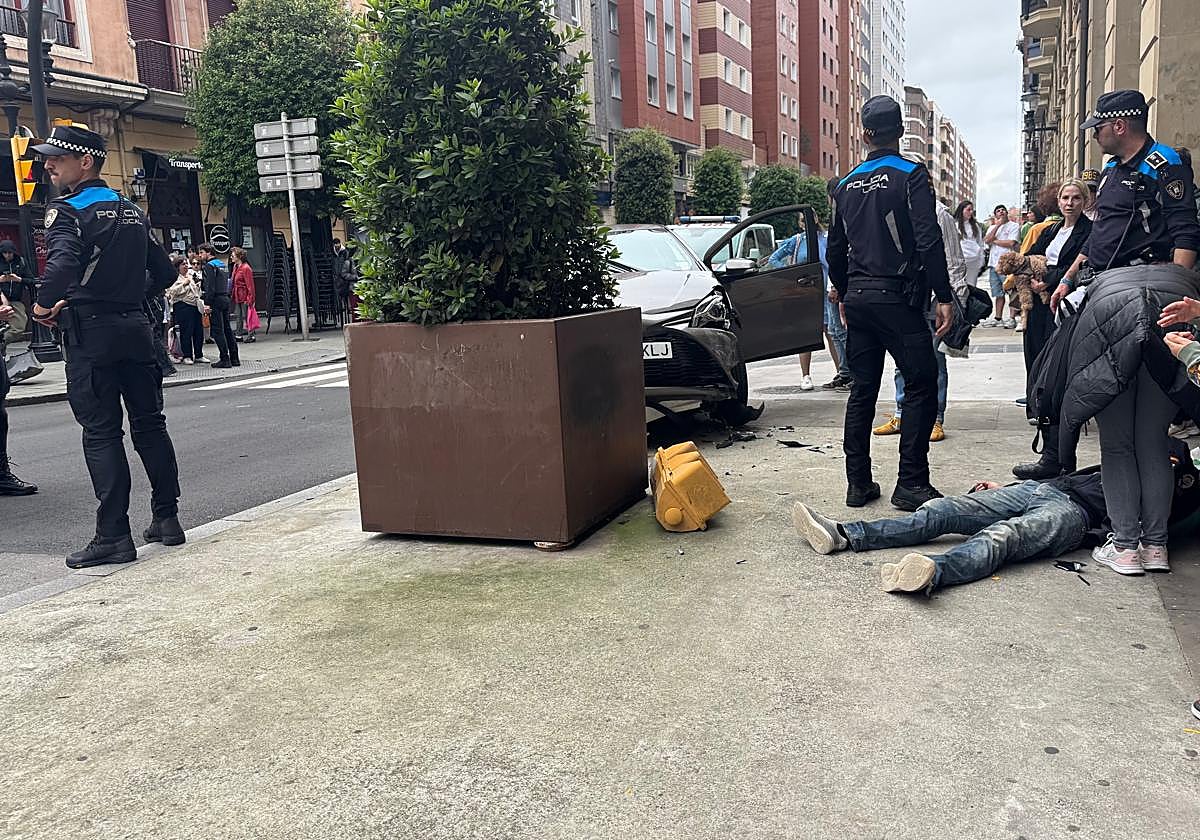 Un coche se sube a la acera en el centro de Gijón y se lleva por delante un semáforo y un peatón