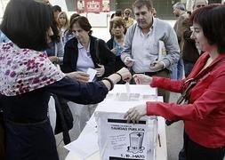 Varias personas depositan su voto sobre la consulta en Madrid. / Efe