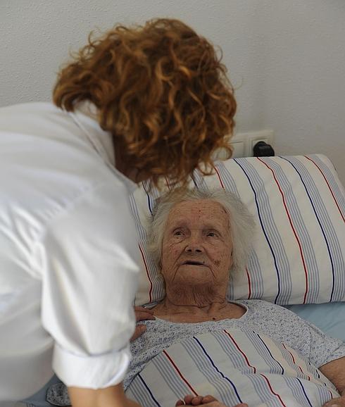 Una trabajadora del Servicio de Ayuda a Domicilio atiende a una anciana. 