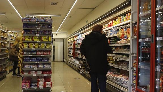 Un cliente mira los productos expuestos en el interior de una tienda de alimentación. 