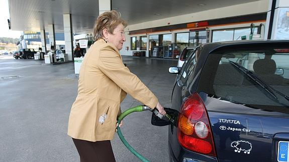 Una mujer repostando en una gasolinera. 