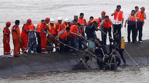 Miembros de los servicios de rescate ayudan a un superviviente tras el naufragio. 