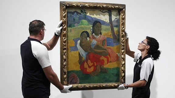 Dos operarios cuelgan el cuadro de Paul Gauguin 'Nafea faa ipoipo'. 