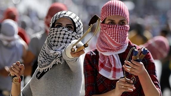 Dos manifestantes palestinas arrojan piedras.