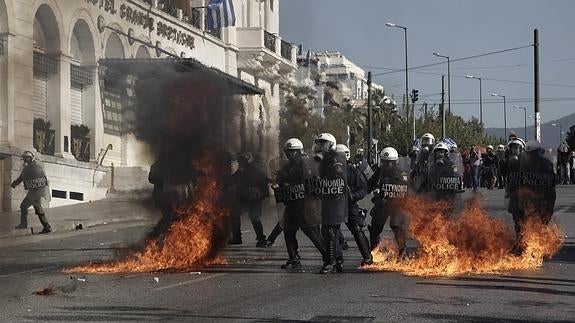 Policías antidisturbios esquivan un cóctel molotov lanzado durante una manifestación contra las políticas de austeridad.