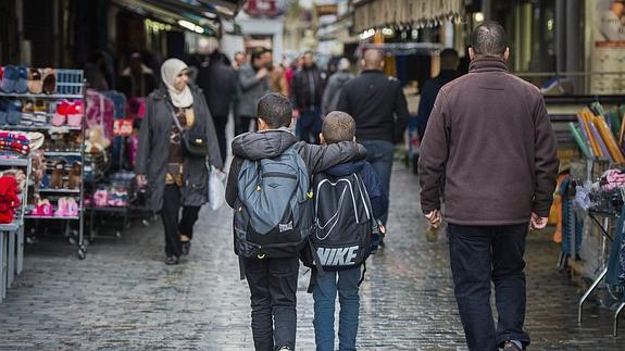 Dos niños caminan abrazados por una calle de Molenbeek. 