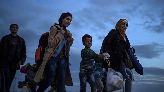 Varios refugiados caminan hacia un campamento de registro y tránsito, en la frontera entre Grecia y Macedonia.